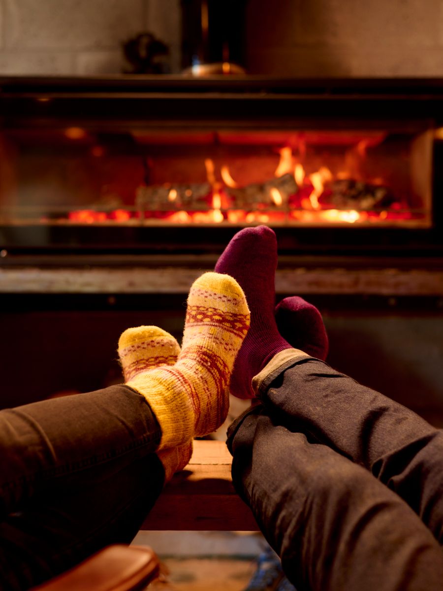 Two pairs of feet with socks on warming by an open fire
