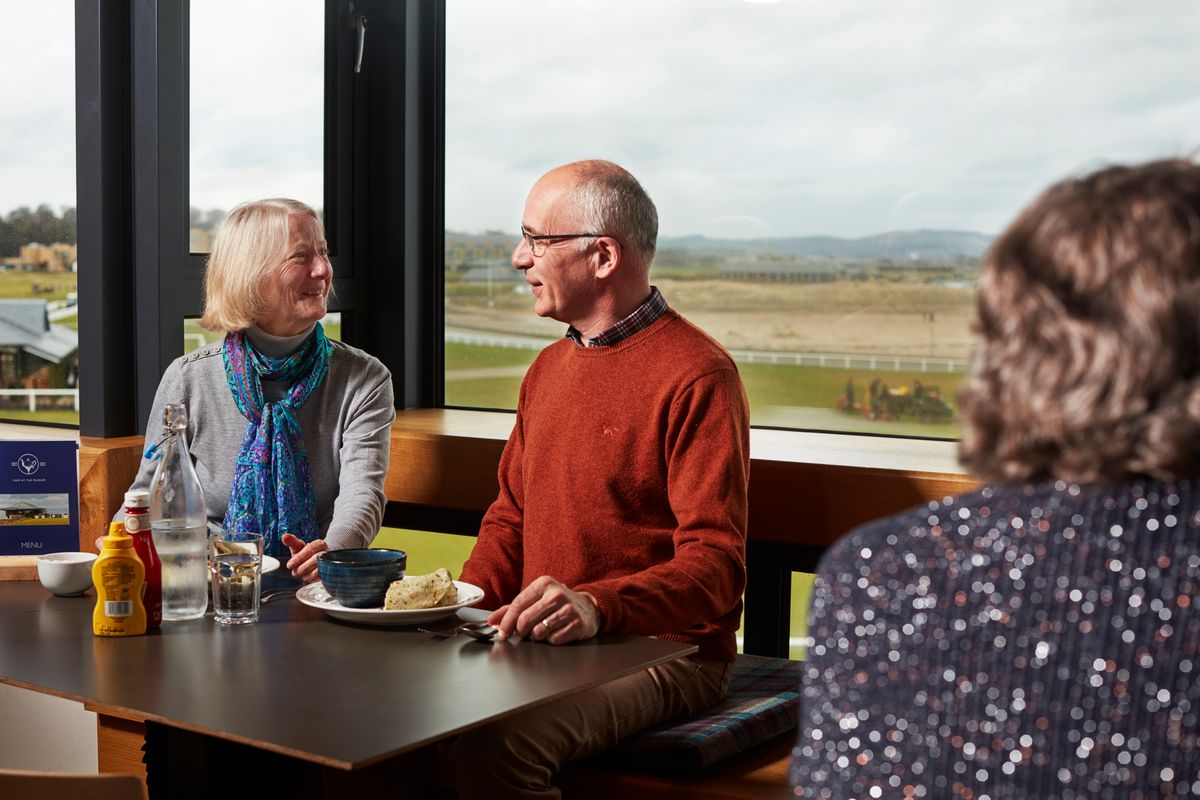 people sitting at a table in a restaurant with views over a golf course in the background