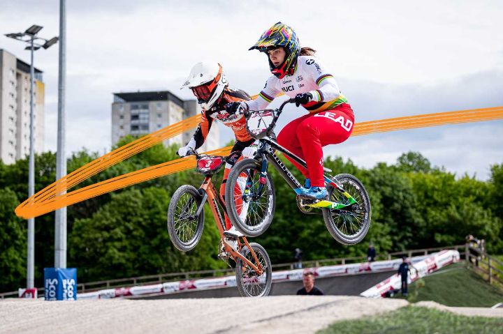 BMX riders going over a jump on a track