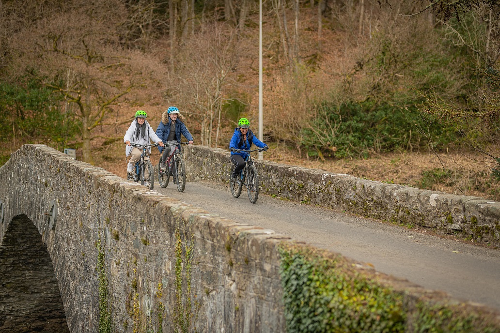 Three people cycling over a bridge during the day