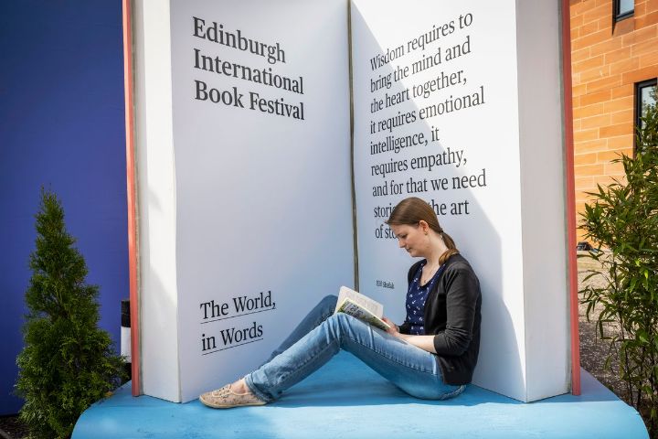 Person reading a book in from of a large sculpture of a book