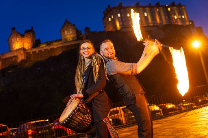 Fire performers posing with torches in front of a castle