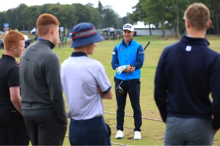 Professional golfer speaking to group of young people on a golf course