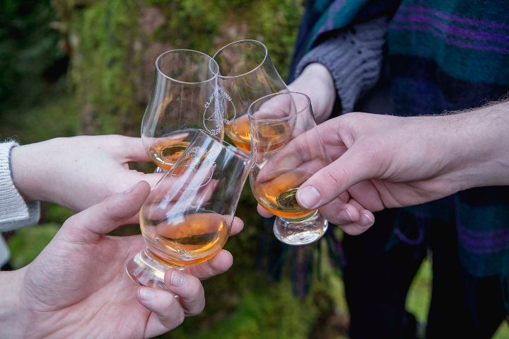 Friends celebrate good health by toasting their glasses of whisky outside the Clachaig Inn in Glencoe