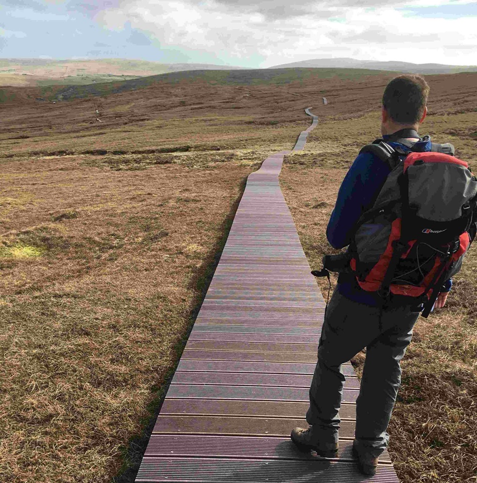 the back of a person walking along a boardwalk