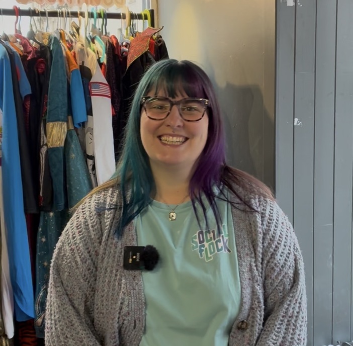 A close up of a person standing indoors and smiling towards the camera