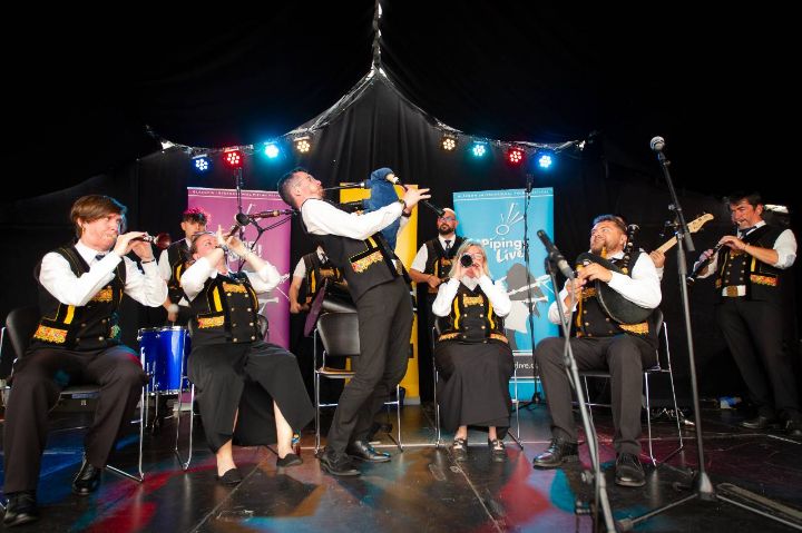 Piping leaning back as he performs on stage with a band