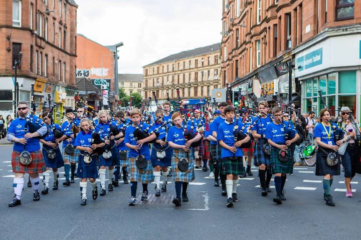 Pipers in matching t-shirts marching through a city while playing