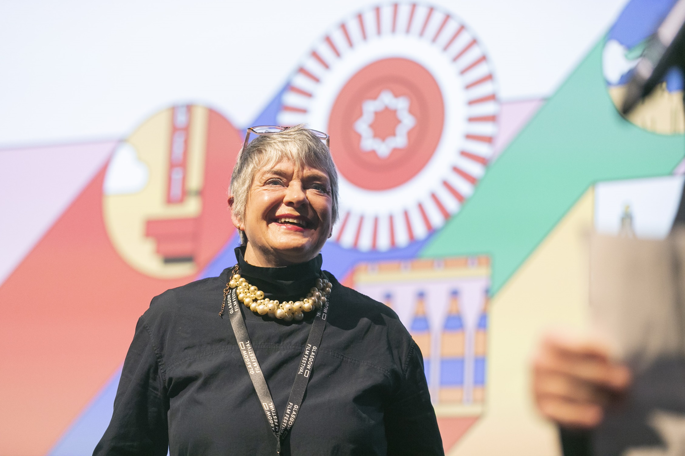 An image of Allison garner smiling, with a colourful illustration behind her.