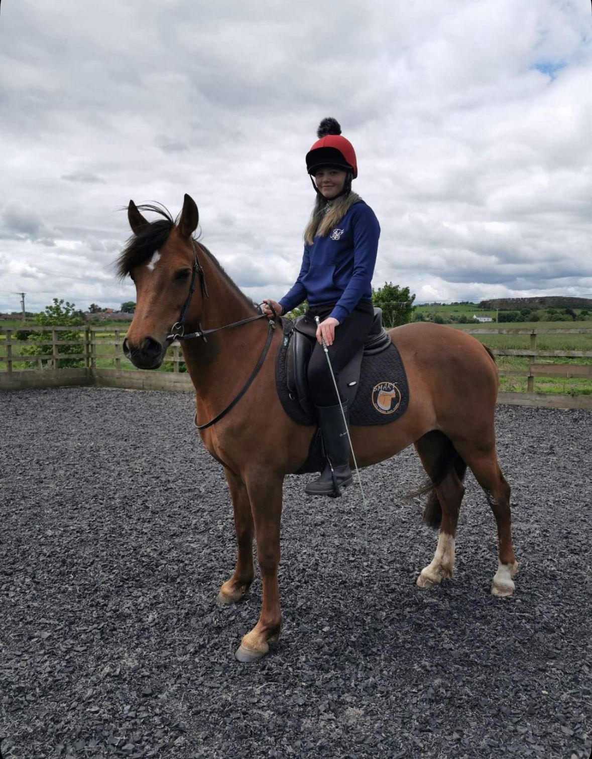 A young volunteer sitting on a horse.
