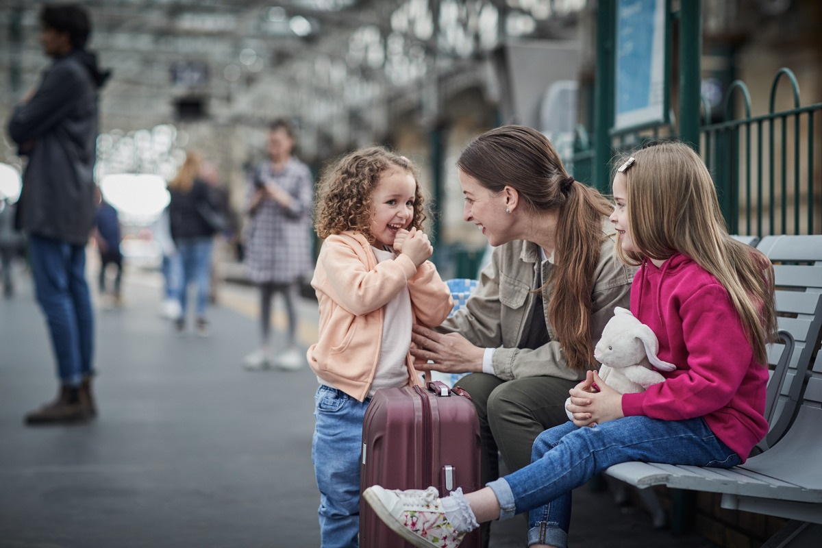 A mother and two children are waiting for their train at the station