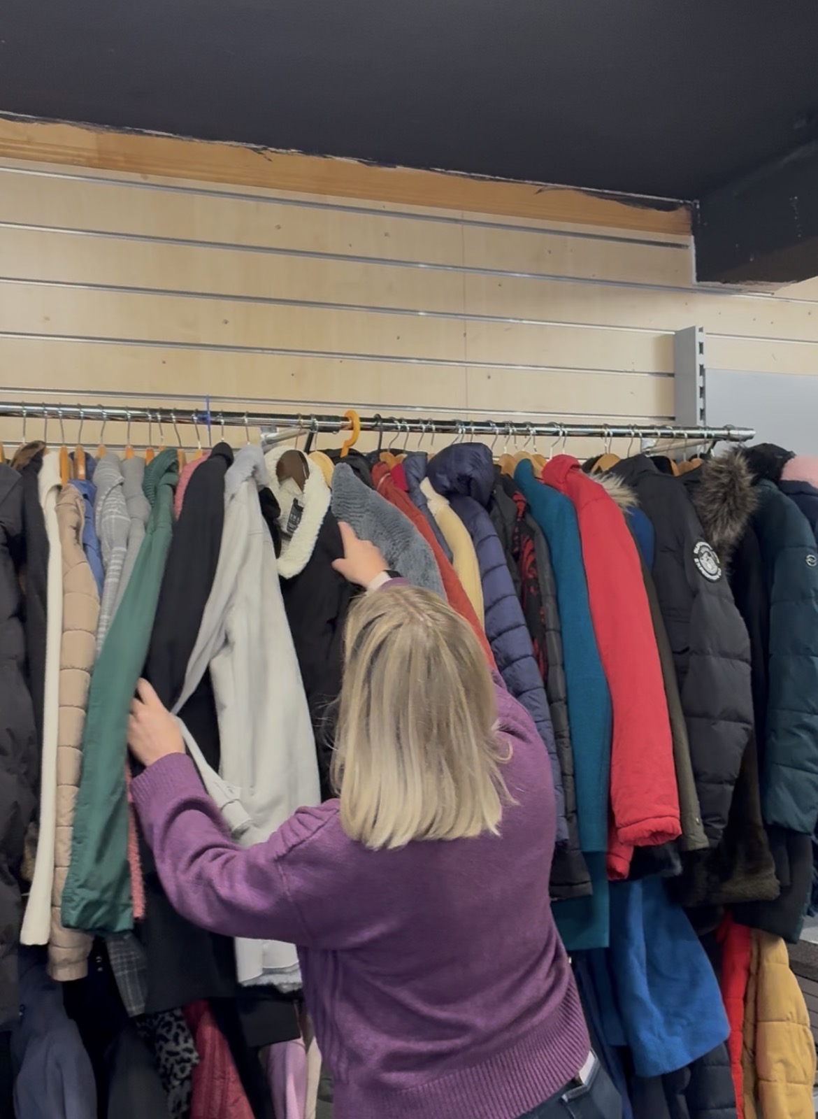 A person looking through a rail of coats