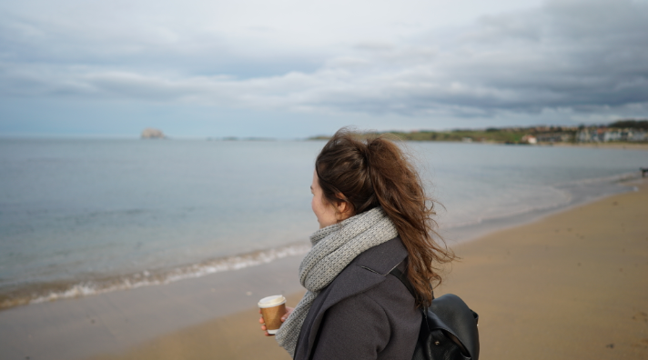 Person standing on a beach looking out towards the water