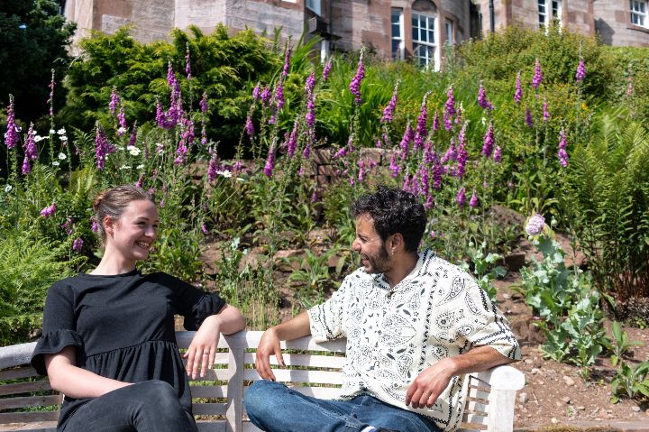 A couple sit on a bench in the garden of Nithbank Country Estate