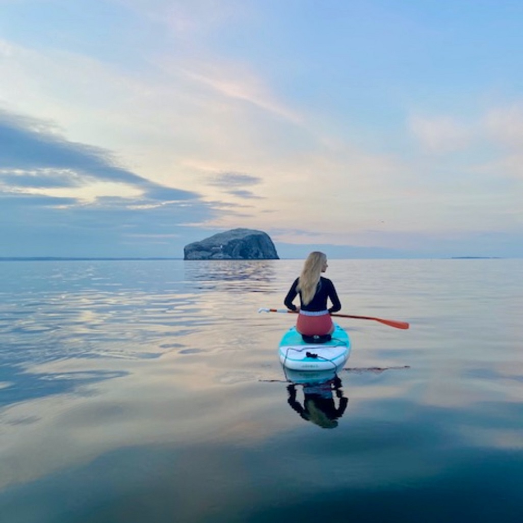 A person on a kayak on the water looking out to sea