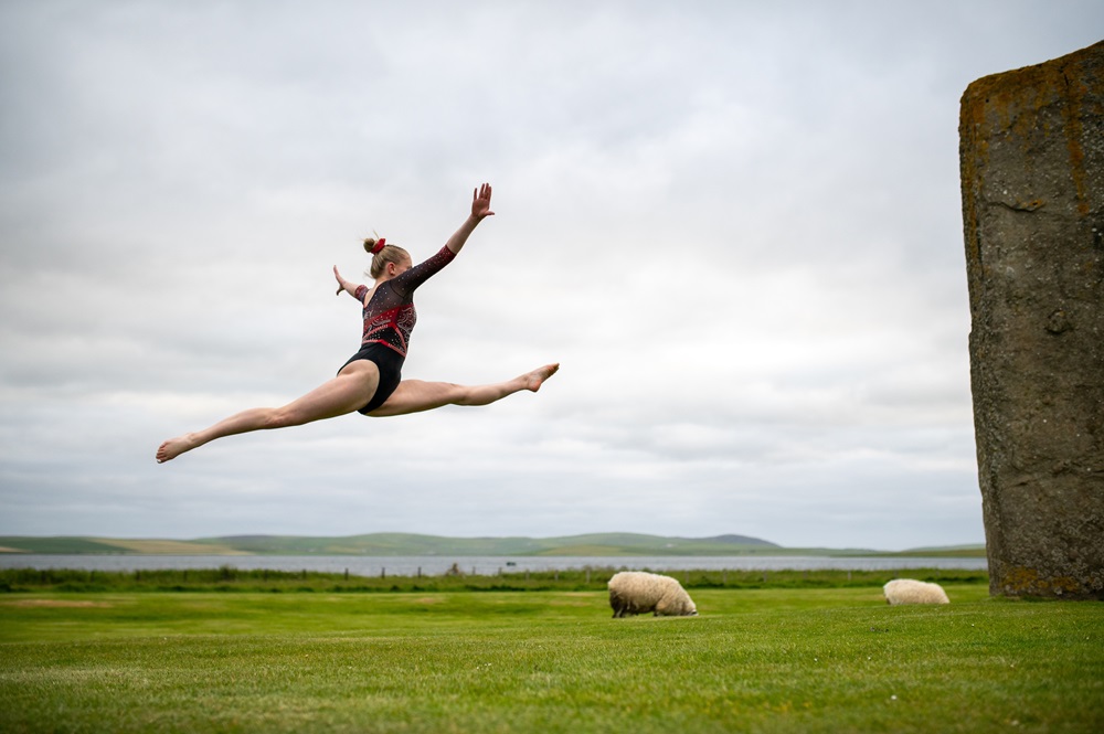 Gymnast jumping in front of a standing stone