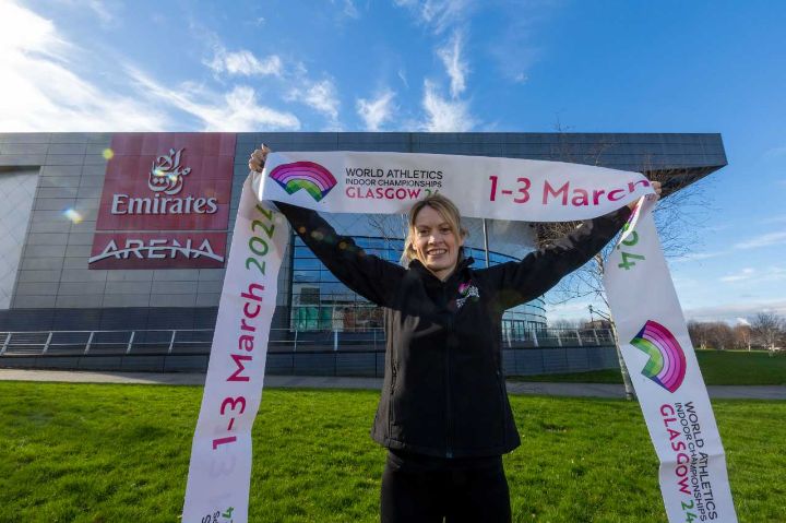 Athlete holding up a banner in from of a sporting arena