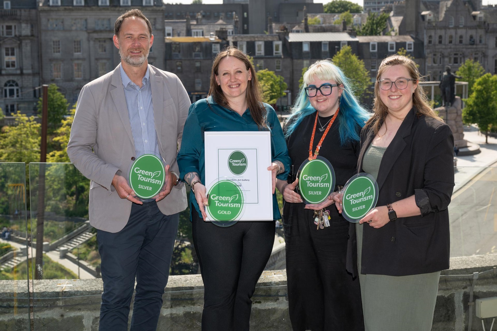 a group of people outside facing the camera, one holding a certificate