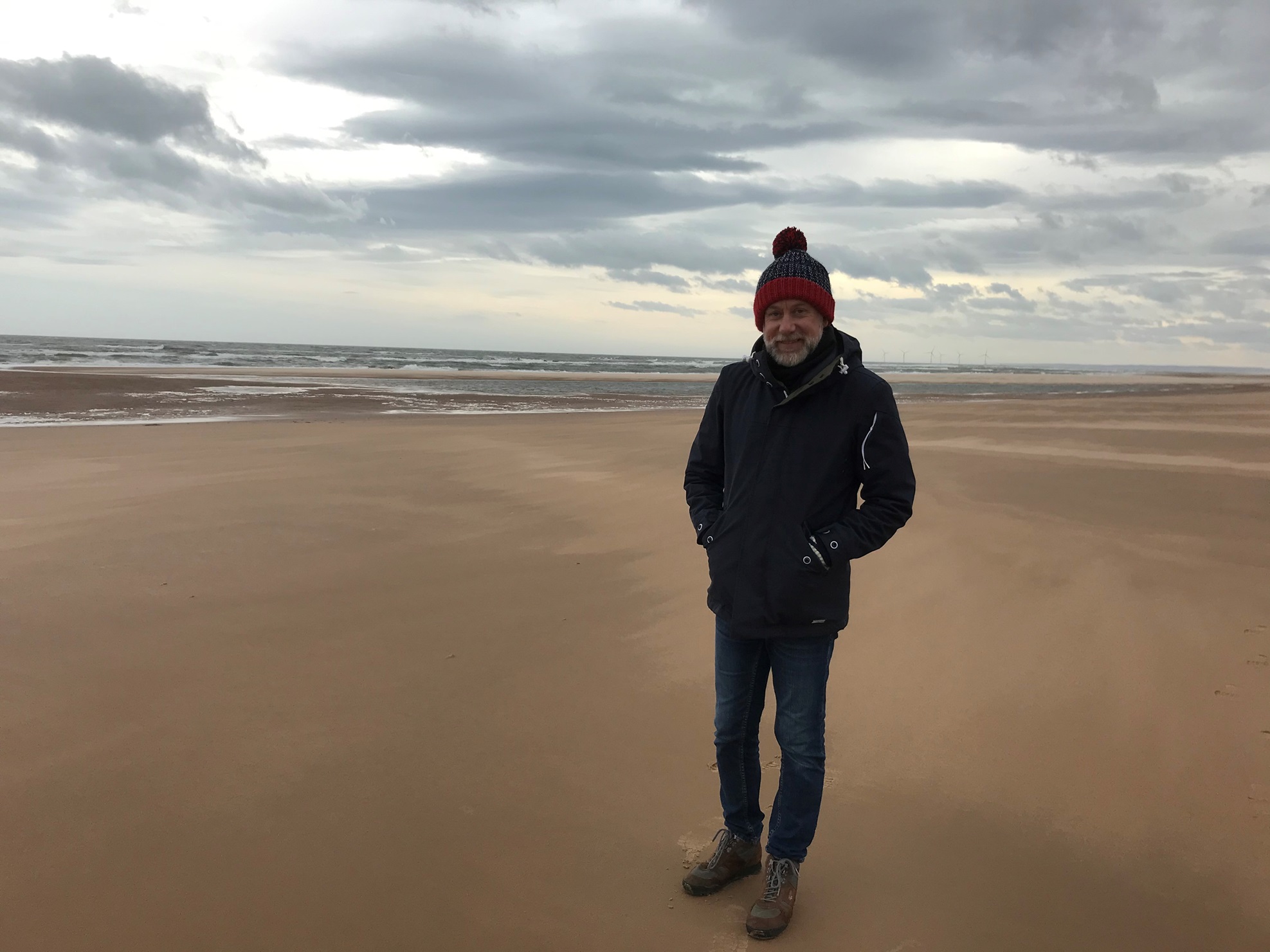 A person standing on a beach, during the day