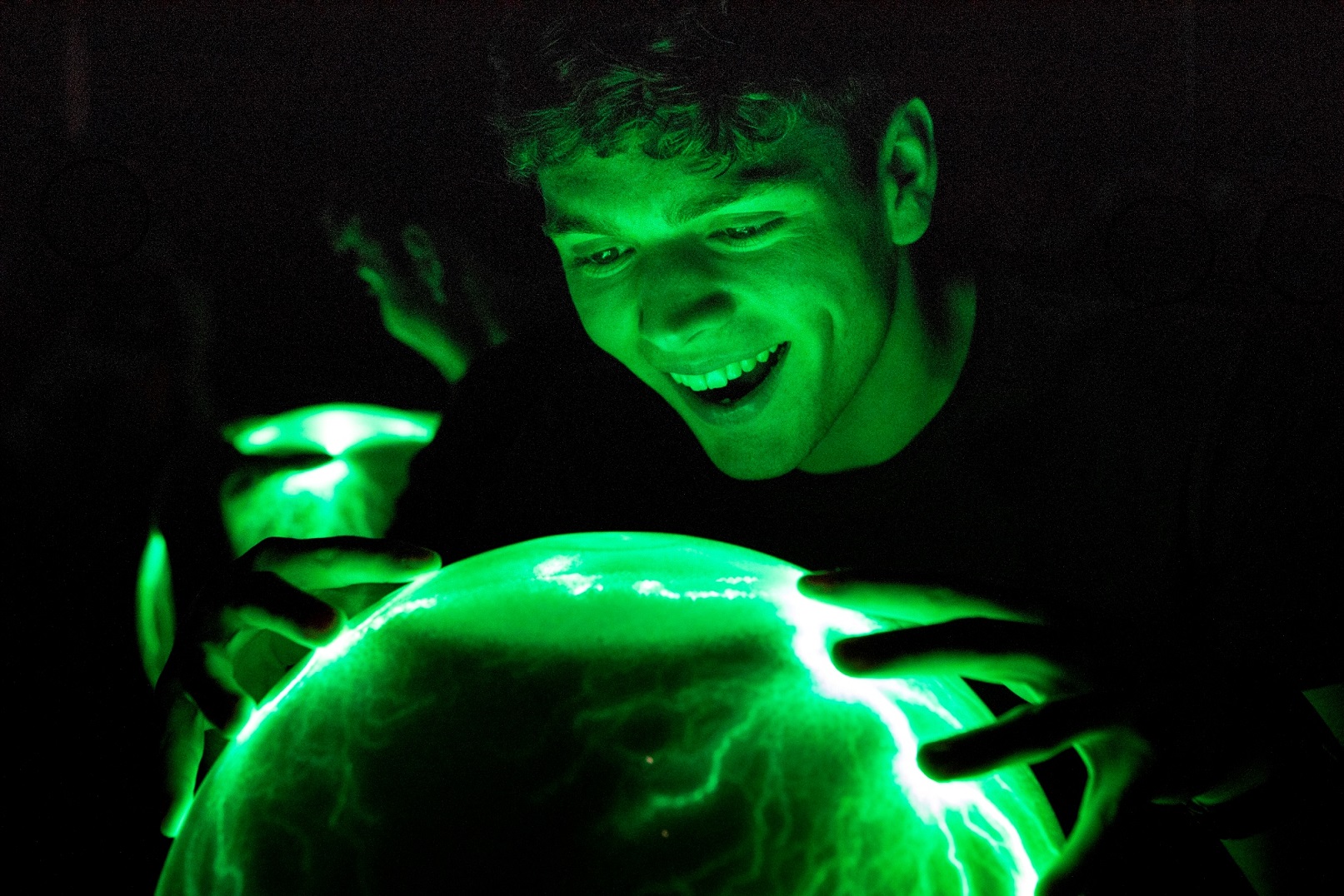 A man looking over sphere with lighting bolts, and illuminated bright neon green.