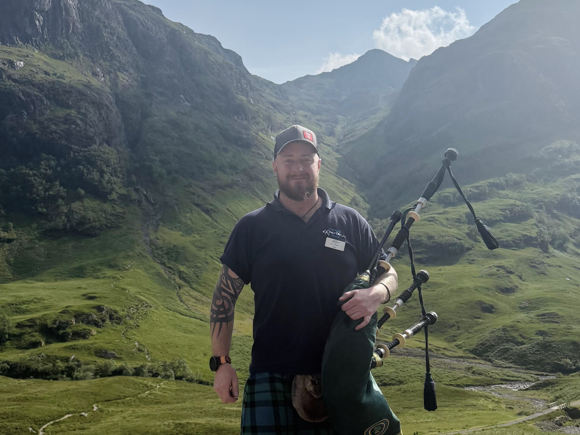 Image of a man standing holding bagpipes and wearing a kilt.
