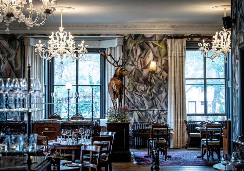 Image of the Clunie Dining Room. A grand dining room, with a stag statue in the middle of the room.