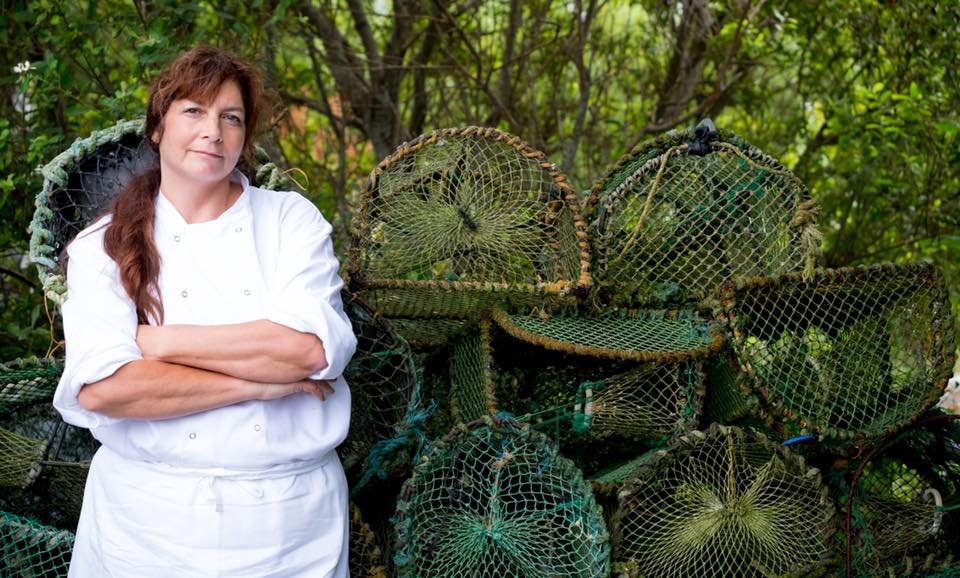 An image of of a chef in front of cages used to catch seafood for restaurant