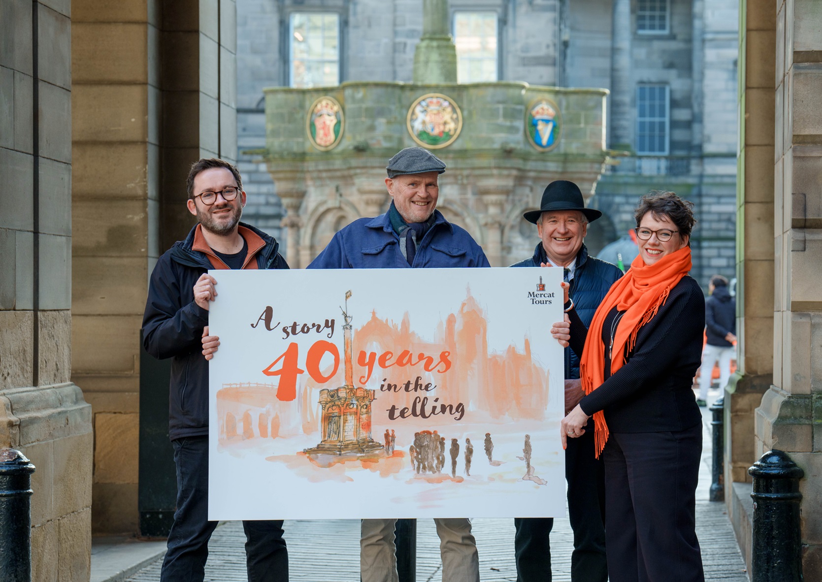 Group of people standing behind a banner that reads "A story 40 years in the telling"